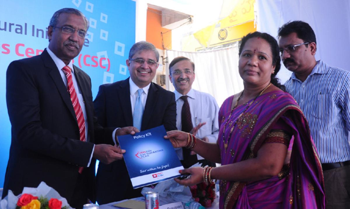 IRDA Chairman T S Vijayan (left) and Amitabh Chaudhry, MD & CEO, HDFC Life, handing over the first policy of HDFC Life CSC Suraksha Plan to P Padma in Hyderabad on Thursday